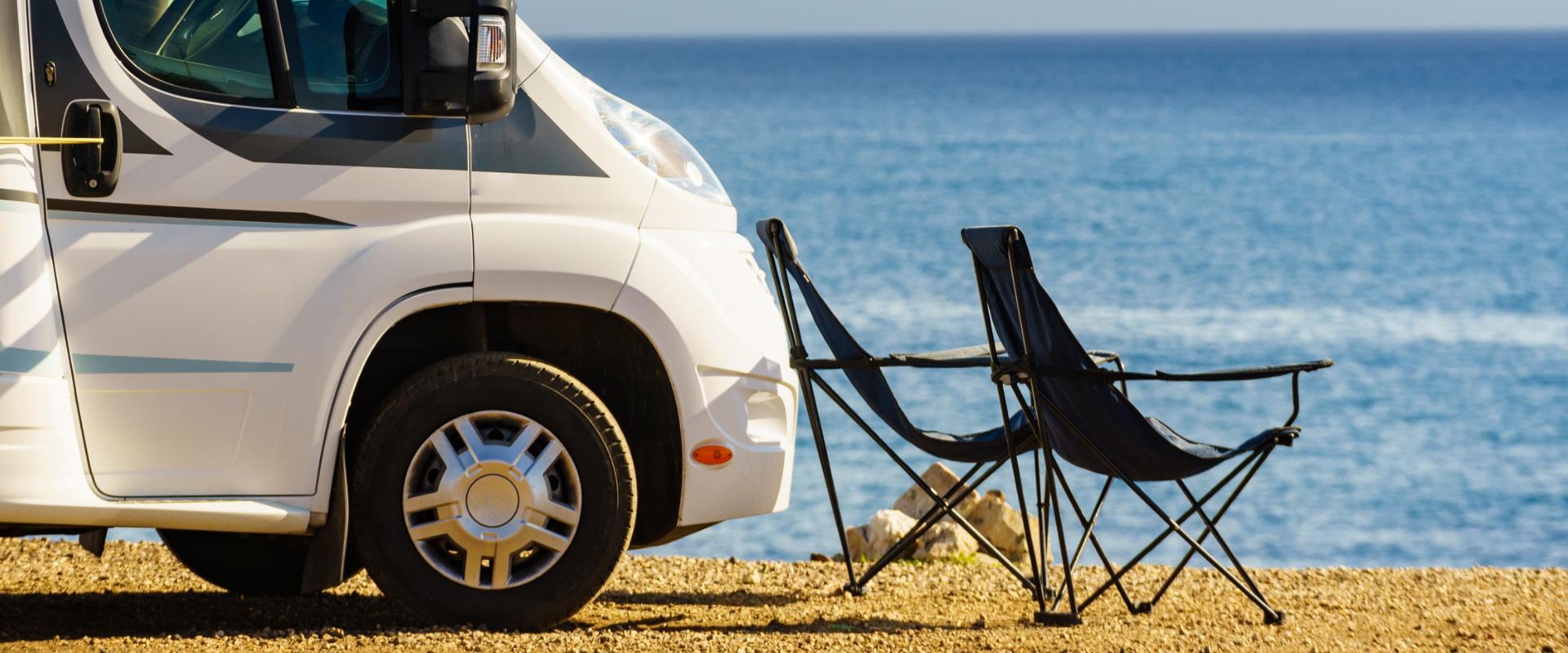 Camper e sedie pieghevoli in riva al mare, atmosfera di relax estivo.
