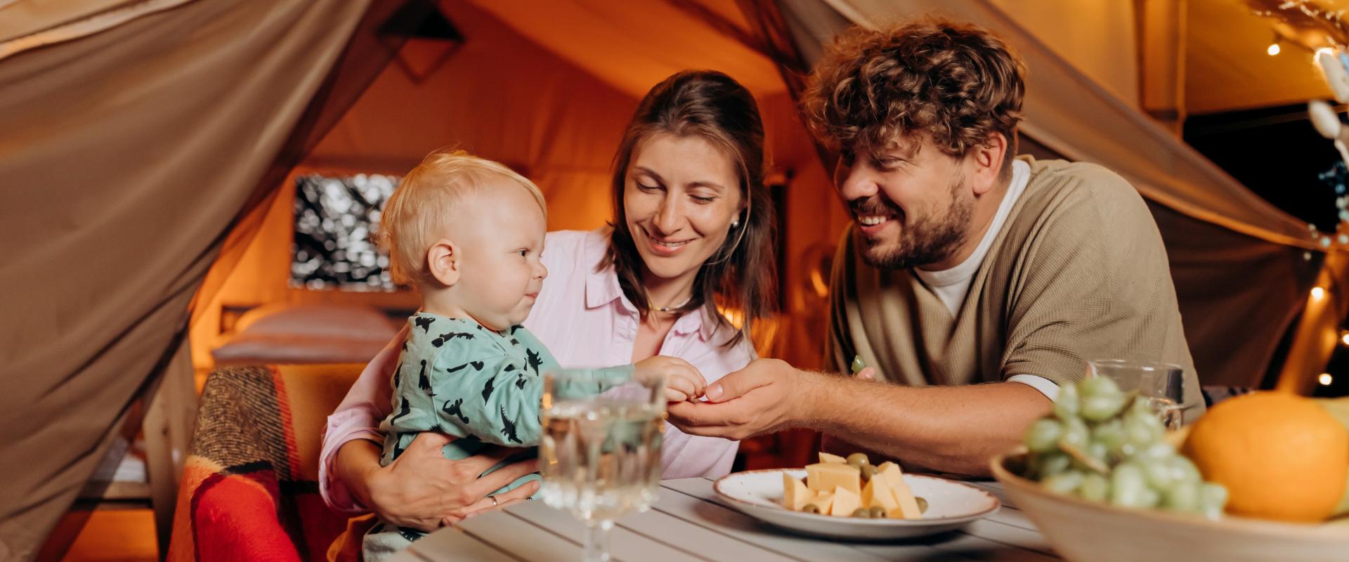 Famiglia felice in campeggio, condividendo un pasto all'interno di una tenda accogliente.