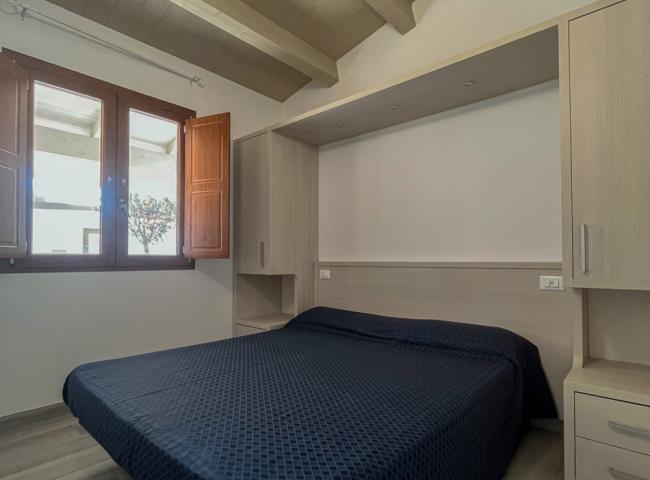 Camera da letto con letto matrimoniale, soffitto in legno e finestra luminosa.