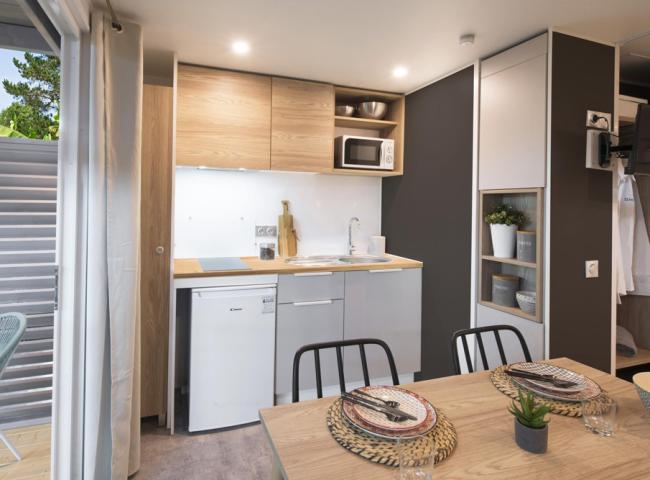 Cucina moderna compatta con tavolo da pranzo, frigorifero e microonde.
