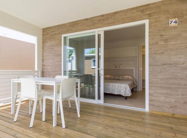 Terrazza con tavolo bianco, sedie e vista su camera da letto moderna.