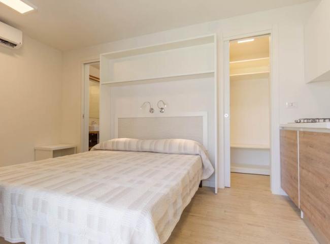 Camera moderna con letto matrimoniale, cucina attrezzata e aria condizionata.