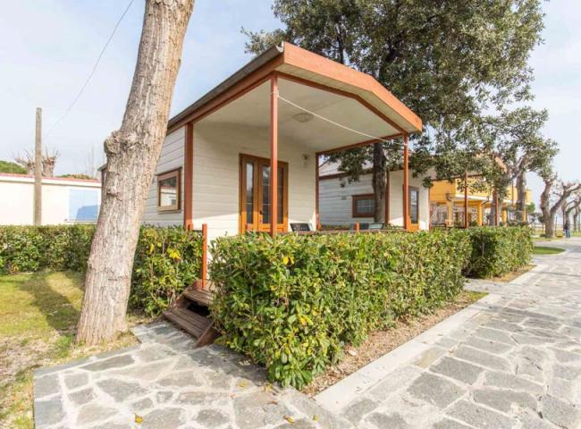 Bungalow con veranda, circondato da siepi, in un ambiente tranquillo e soleggiato.