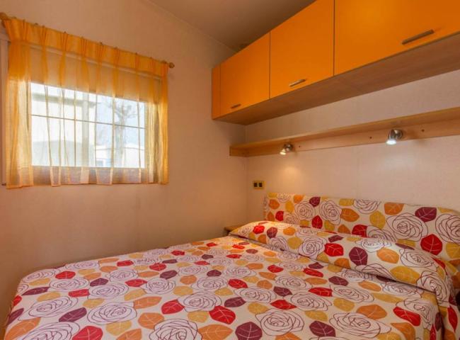 Camera da letto con copriletto floreale e pensili arancioni.