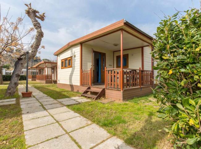 Bungalow in legno con veranda, immerso nel verde, ideale per vacanze rilassanti.