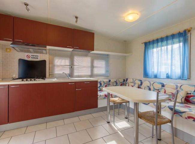 Cucina moderna con divano angolare, tavolo e sedie, vietato fumare.