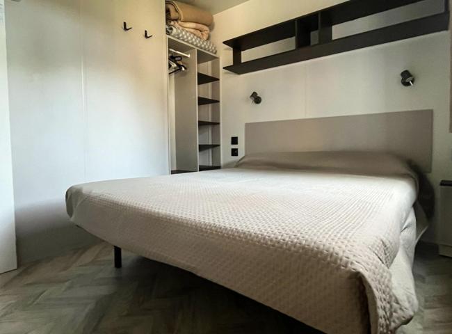Camera da letto moderna con letto matrimoniale e armadio aperto, pavimento a spina di pesce.