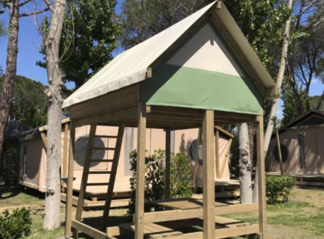 Piccola struttura in legno con tetto a spiovente in un campeggio.