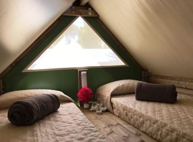 Interno di una tenda con due letti, coperte e decorazioni floreali.
